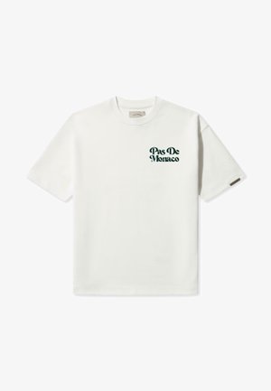 Baltos medvilnės marškinėliai su trumpomis rankovėmis ir apvalia kaklo iškirpte. Kairėje krūtinės pusėje yra žalia teksto dizaino frazė "Pas De Monaco".