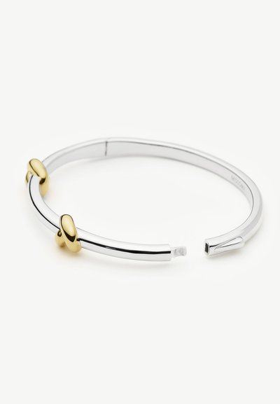 Ανοιχτό βραχιόλι από ασήμι με δύο χρυσές οβάλ λεπτομέρειες, εμφανίζεται σε λευκό φόντο.