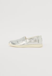 Silberne Slipperschuhe mit metallischem Finish, abgerundeter Zehenpartie, elastischen Seitenpaneelen und einer hellgrauen Gummisohle. Einfaches Design ohne Muster oder Akzente.