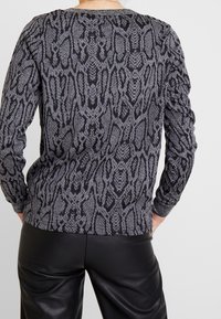Maglia a maniche lunghe con stampa di serpente nera e grigia, tessuto testurizzato e dettagli a costine sul colletto e sui polsini.
