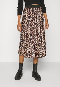 Gonna midi plissettata con una stampa leopardata in tonalità di marrone e beige, con una vita elasticizzata e abbinata a stivaletti neri.