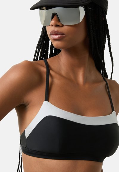 Černý bikini top s světle šedými akcenty, s tenkými ramínky a geometrickým vzorem. Hladký materiál s kontrastními barevnými bloky.