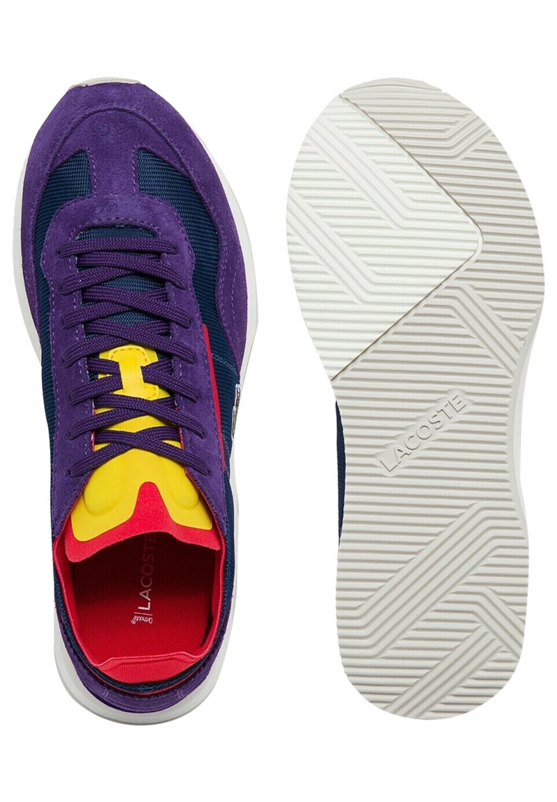 Lacoste sneakers i lila mocka och mesh, med gula och röda detaljer, och en vit gummisula med ett strukturerat mönster.