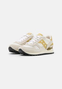 Beige suède en mesh sneakers met gele accenten, witte veters en een zwarte rubberen zool. Voorzien van een gevoerd kraag en verstevigde hiel.