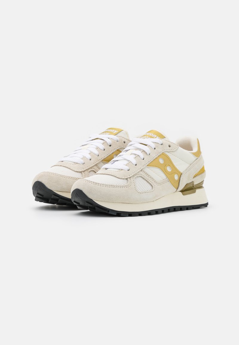 Sneakers beige in suede e rete con accenti gialli, lacci bianchi e suola in gomma nera. Presentano un colletto imbottito e un tallone rinforzato.