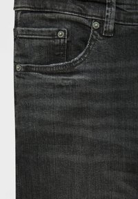 Tissu en denim noir avec couture détaillée de la poche avant et rivets métalliques sur les jeans.