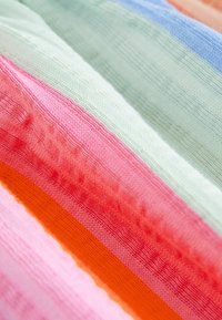 Multikleurig textiel met horizontale strepen in pastelgroen, roze, oranje en lichtblauw. Heeft een textuur oppervlakte en variërende diktes.