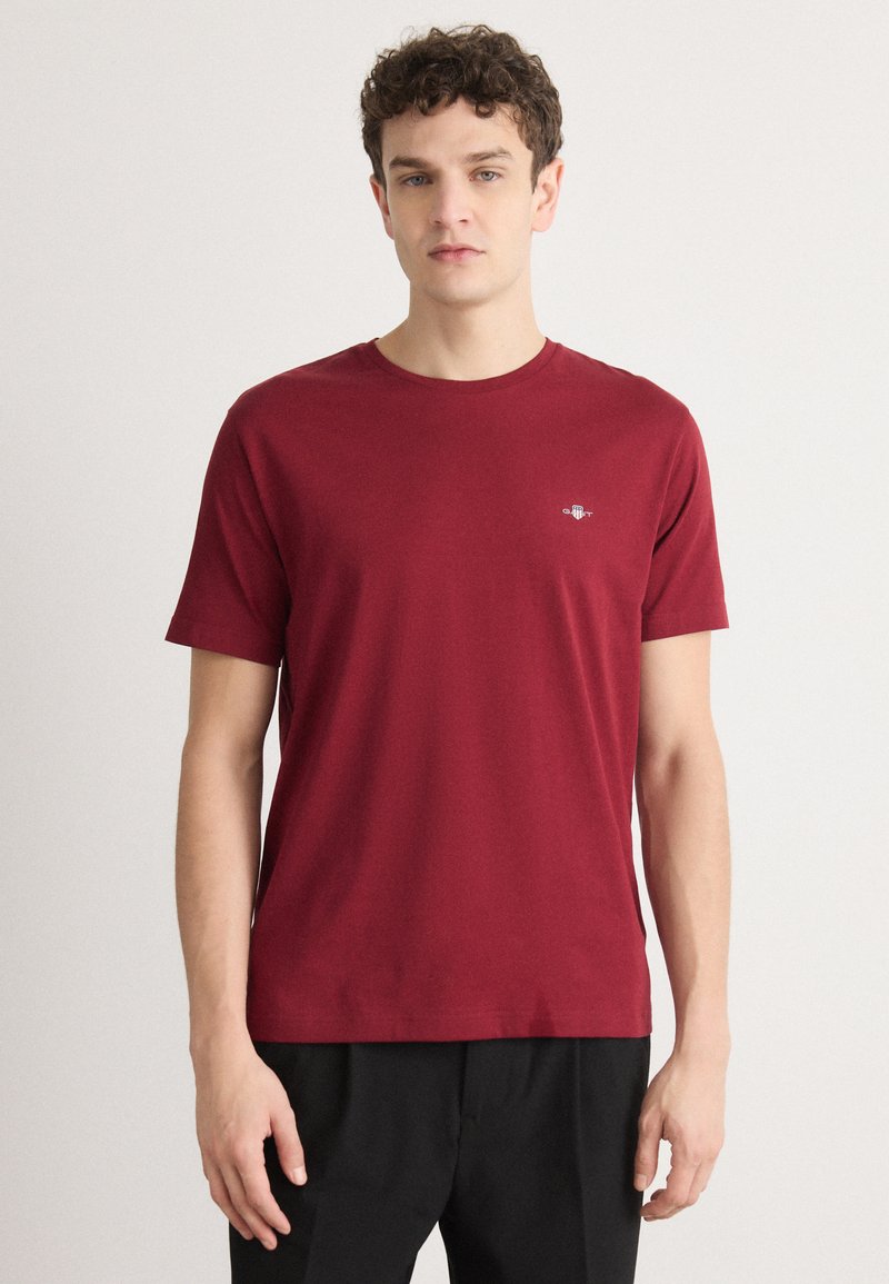 Bordå kortärmad t-shirt i bomull med rund halsringning och en liten logodetalj på bröstet, i kombination med svarta byxor.