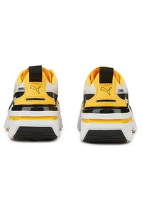 Sneaker Puma con una combinazione di colori bianco, nero e giallo brillante, dotate di una suola spessa, accenti testurizzati e un logo ben visibile.