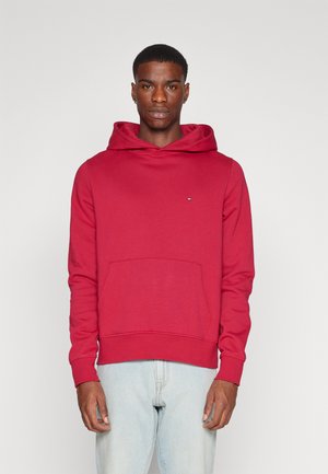 Sudadera roja de tela suave, con un bolsillo frontal, capucha ajustable con cordón y un sutil detalle de logo en el pecho.