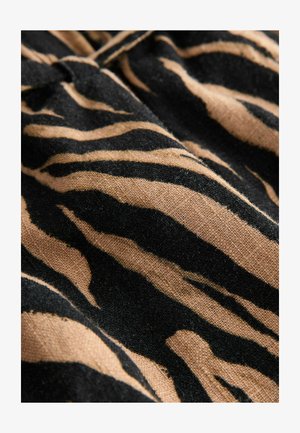 Svart och brunt zebramönstrat tyg med en mjuk textur och framträdande alternerande ränder, med synliga fibrer för extra detalj.