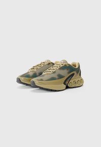 Green and tan mesh sneakers with a rounded, textured sole, featuring a prominent Nike logo and camouflage pattern.
