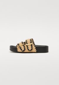 Sandalo scivoloso in paglia intrecciata beige con accenti neri e due fibbie regolabili. Presenta una suola spessa in gomma nera e un motivo testurizzato.