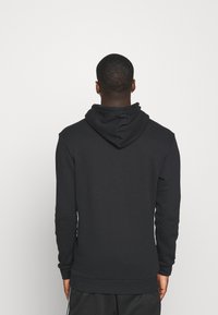 Svart huoodad sweatshirt i mjukt material. Har långa ärmar, en avslappnad passform samt ribbade fållar och muddar. Minimalistisk design.