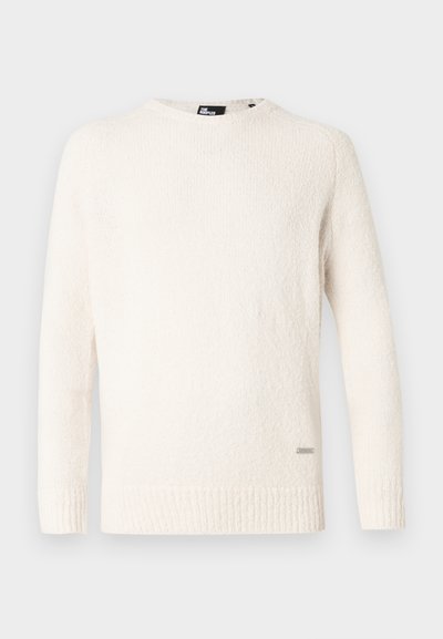 White textured sweater with long sleeves, ribbed hem, and crew neck. Features a small brand tag stitched on the lower side.