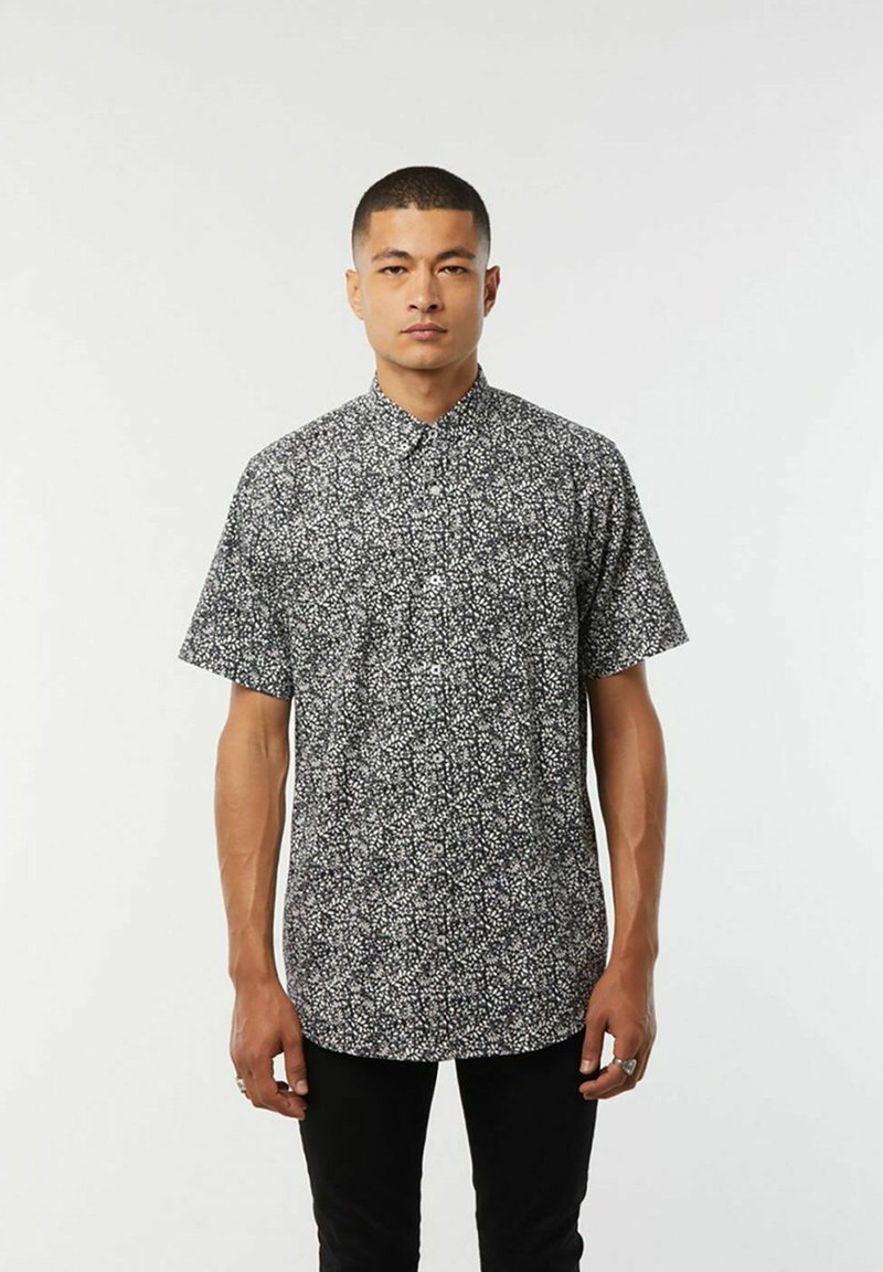 Korte mouw knoopshirt in zwart met een wit bloemenpatroon. Heeft een klassieke kraag en een rechte snit. Soepele stofstructuur.