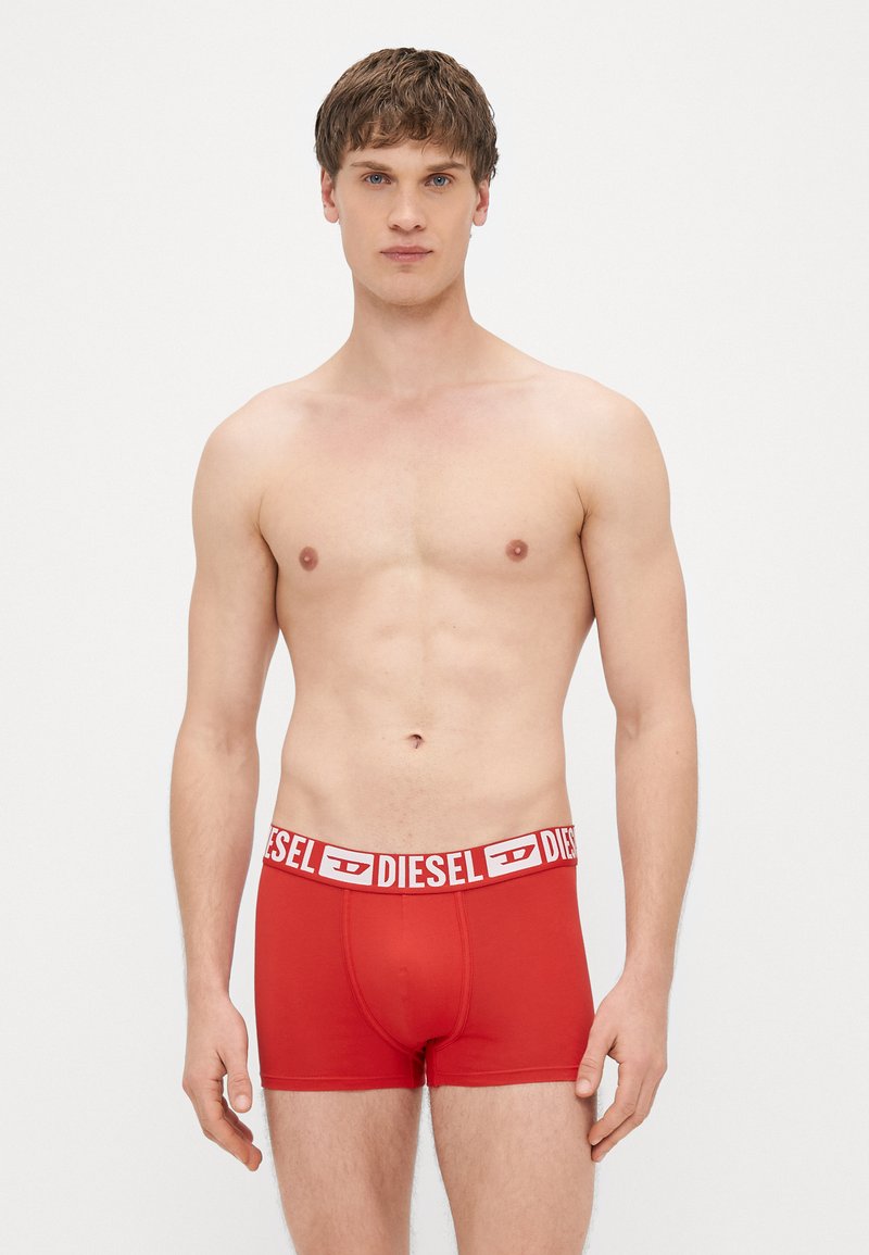 Punased puuvillased bokserpüksid valge elastse vöökohaga, kus on kiri "DIESEL". Silmapaistev tekstuur ja keha ümbritsev lõige.