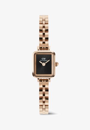 Rózsa arany fém szíjas óra téglalap alakú fekete számlappal, arany mutatókkal és a "DW Daniel Wellington" logóval a számlapon.