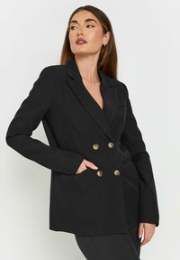 Svart dubbelknäppt blazer med slag, guldtonade knappar och en enkel ficka. Tillverkad av slät tyg med en skräddarsydd passform.