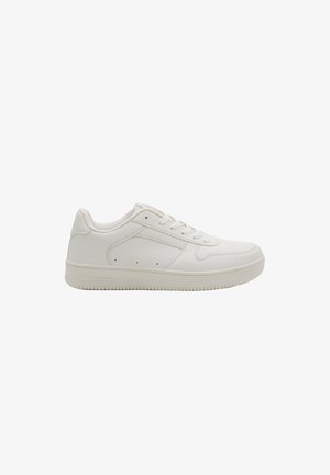 Zapatilla blanca de corte bajo con cierre de cordones, cuello acolchado y suela de goma texturizada, mostrada de perfil sobre fondo blanco.