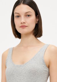 Grijze mouwloze top gemaakt van zachte, lichte stof met een ronde halslijn en een minimalistisch ontwerp, met een glad, iets gestructureerd oppervlak.