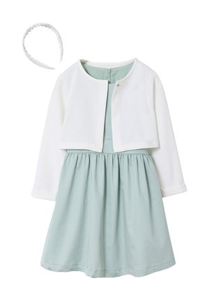 Hellblaues, ärmelloses Kleid mit gerafftem Rock, kombiniert mit weißer, langärmeliger, kurzer Strickjacke und passendem weißen, gewellten Haarband.