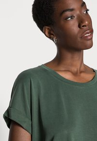 Green short-sleeved t-shirt with a wide neckline and rolled cuffs, made of soft fabric, featuring smooth texture and relaxed fit.
