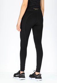 Zwarte leggings met een stevige pasvorm en zichtbare naden. Voorzien van een hoge tailleband en een logo-detail op de achterkant. Draag ze met zwarte sneakers.