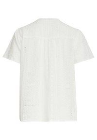 White short-sleeve shirt featuring a textured eyelet pattern, with rows of circular cutouts and a relaxed silhouette.
