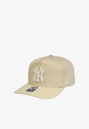 Beige New York Yankees baseball cap with flat brim and white embroidered logo on front, showing brand sticker on brim.