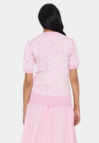 Kortärmad rosa tröja med ett ljusrosa abstrakt mönster. Har ribbade ärmslut och nederkant, med en slät yta.