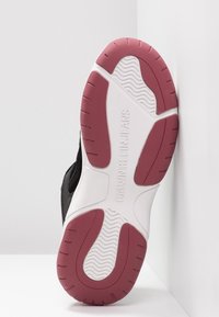 Semelle de sneaker Calvin Klein Jeans avec un dessus noir, une semelle intermédiaire blanche, une semelle extérieure en caoutchouc rouge avec un motif de crampons en zigzag et un logo de la marque.