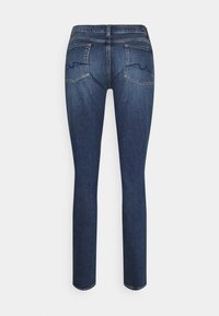 Jeans ajustados de denim azul oscuro. Presentan dos bolsillos traseros con detalles de costura curva, cinturilla estándar y textura suave.