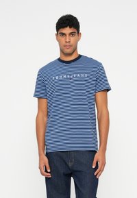 Ribaga lühikeste varrukatega T-särk tumesinises ja helesinises, ümar kaelus ja "TOMMY JEANS" logo rinna ülaosas.