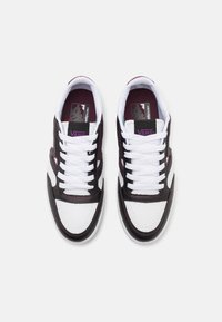 Black and white sneakers with a smooth leather upper, padded tongue, and white laces. Features purple accents and a textured insole.