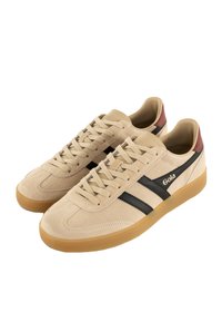 Zapatillas de ante beige con rayas negras y una tapa de talón marrón. Presentan un diseño de cordones y una suela de goma. Logotipo de Gola visible.