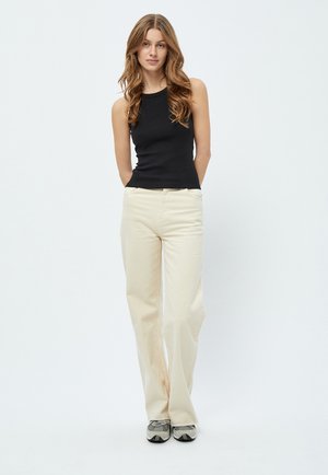 Haut sans manches noir, pantalon large crème et chaussures à motifs. Textures lisses et design ajusté avec une silhouette décontractée et relax. 