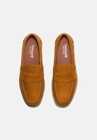 Ruske nubuk mokasini s zaobljenim prstima, dekorativnim šavovima i trakama preko gornjeg dela. Udobna unutrašnjost sadrži Timberland brend.