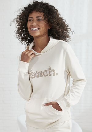 Cremefarbener Hoodie mit einer Fronttasche, der ein reflektierendes "Bench."-Logo zeigt. Hergestellt aus weichem Stoff mit Rippbündchen und Kapuze.