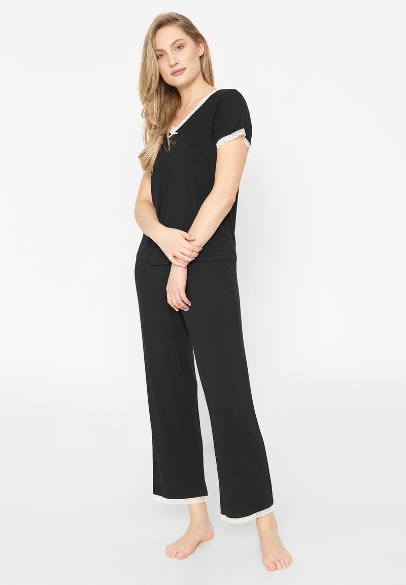 Ensemble de pyjama noir comprenant un haut à manches courtes avec des bordures en dentelle et un pantalon avec des accents en dentelle à l'ourlet. Matériel doux et léger.