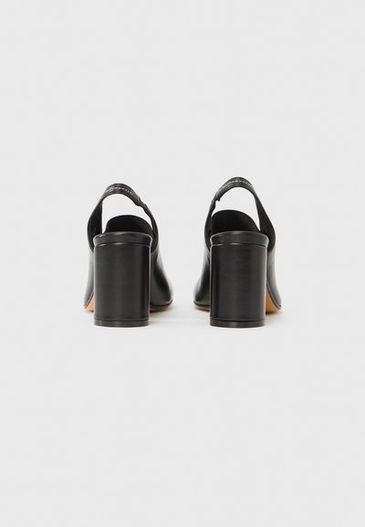 Fekete bőr magassarkú cipők pántos hátoldallal, négyzet alakú orral és blokk sarkakkal. Simább textúra, finom varrással.