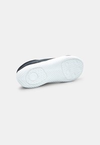Sole di sneaker atletici neri con fondo in gomma bianca. Presenta un motivo di grip testurizzato e accenti circolari. Progettata per trazione e durata.