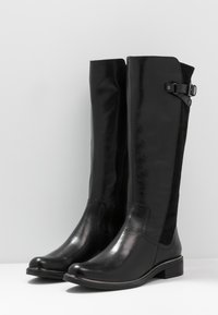 Černé kozačky sahající po kolena z hladké kůže s texturovaným bočním panelem, kulatou špičkou a dekorativní sponou na vnější straně holeně.