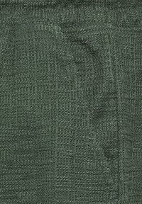 Dark green fabric with a textured, small-checkered pattern and a folded corner showing looped yarn details.