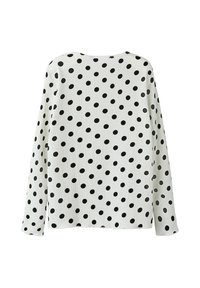Witte lange mouw top met een gestructureerde stof en grote zwarte stippen, ronde halslijn en een iets losse pasvorm.