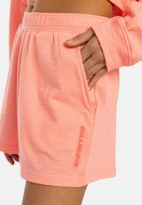 Lichte, getextureerde perzikkleurige shorts met een elastische tailleband, zijzakken en een logo-afdruk in een bijpassende tint aan de zijkant.
