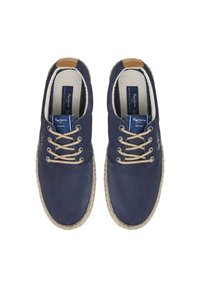 Zapatillas de lona navy con punta redondeada, costuras beige y suela de estilo espadrille tejida. Presentan detalles de goma y cordones beige.