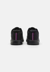 Svarte joggesko med mesh-overdel, som har en teksturert finish, bakre lilla stripe og polstret såle for støtte. To-delt design.