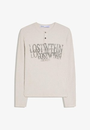 Bézs színű bordázott, hosszú ujjú henley póló három gombbal és a mellkason átfedő, kopott hatású "LOST WITHIN" felirattal.