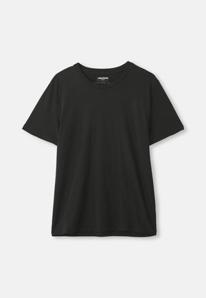 T-shirt noir à manches courtes et col rond accroché devant un fond blanc uni, étiquette visible à l'intérieur du col.